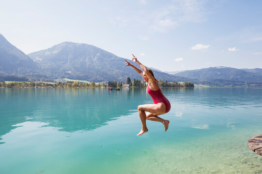 Austria, Alps, Salzburg, Salzkammergut, Salzburger Land, Wolfgangsee, woman jumping into lake