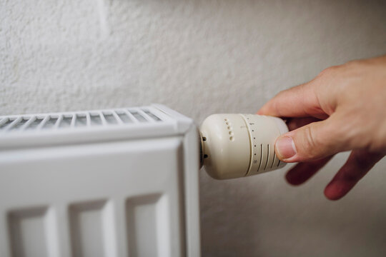 Mature man adjusting temperature with regulator of radiator in front of wall