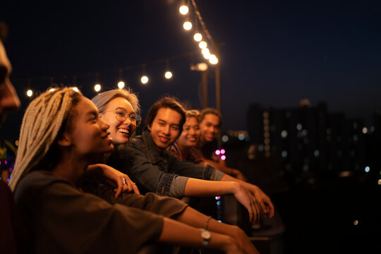 Smiling friends spending leisure time on rooftop at night