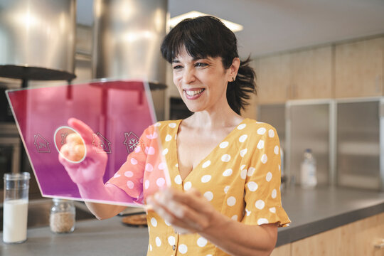 Happy mature woman using digital tablet in kitchen at home