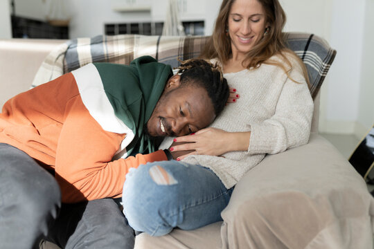 Happy man putting head on pregnant woman's belly sitting at home
