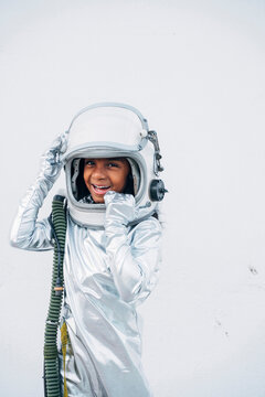 Portrait of laughing little girl wearing space suit and space hat in front of white background