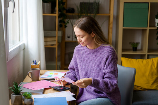 Woman budgeting with calculator and papers at home desk