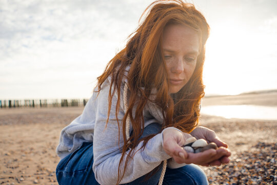 Netherlands, Zeeland, portrait of redheaded woman with collected seashells on the beach