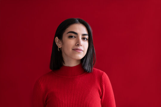 Confident young woman against red background