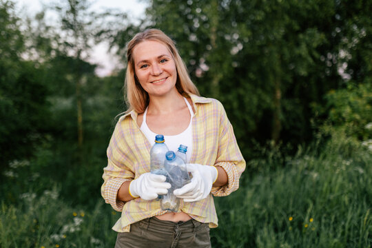 Smiling woman collects plastic waste in nature