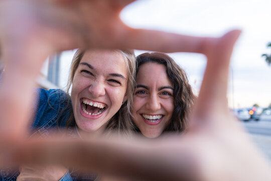 Women smile through a finger frame outdoors