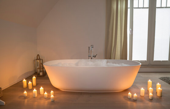 Modern bathtub with lighted candles arround