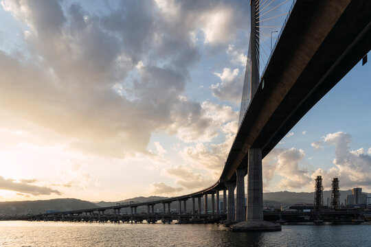 A modern cable-stayed bridge spans the sea at sunset in Cebu