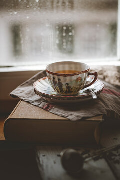Chinese green jasmine tea in a teacup on a book by a rainy window