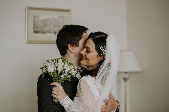 Groom embracing smiling bride at home