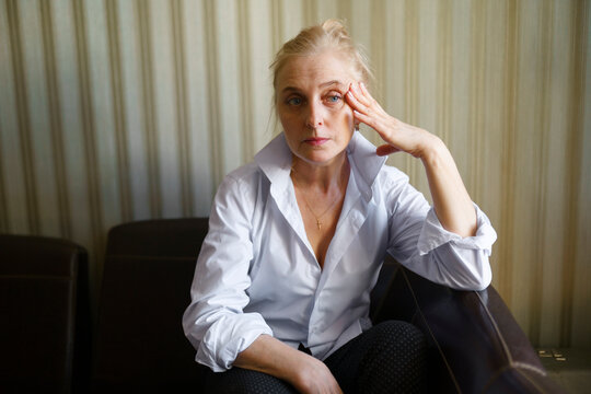 Thoughtful woman wears a white blouse at home