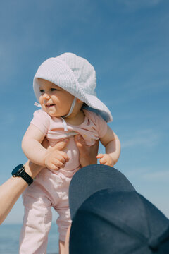 Father holds his baby in a sun hat outdoors during summer vacation