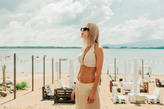 A stylish blond woman enjoys a summer vacation at a sandy lake beach