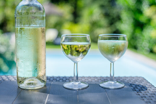 Bottle and two glasses of white wine on outdoor table