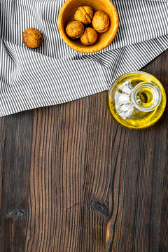 Oil as cosmetics. Walnut oil near walnut in nutshell on dark wooden background top view copy space