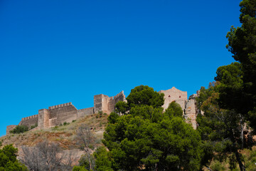 Fototapeta premium Ancient defensive walls of Sagunto Castle overlooking the historic town in Valencia, Spain. A remarkable hilltop fortress with centuries of history surrounded by Mediterranean vegetation.