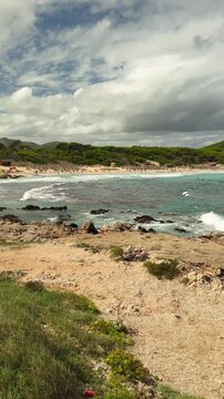 Vertical view of Cala Agulla beach with visitors enjoying  Mediterranean coast in Mallorca, Spain. Travel destination, tourism, seaside recreation, summer vacation. 