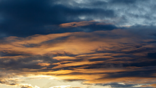Sunset sky with dark blue and golden orange clouds