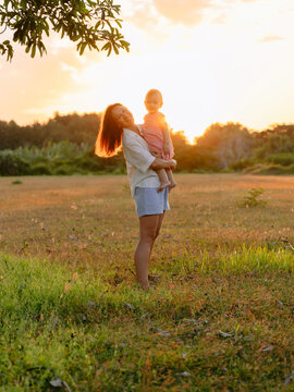 Family moment with mother and her little daughter outdoor with sunset in park