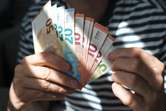 A euro banknote in a man's hand.
