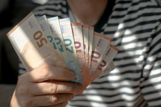 A euro banknote in a man's hand.
