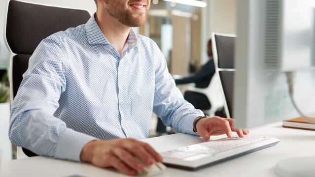 Close up of Caucasian man using desktop computer in office. Close-up of hands typing on keyboard in cabinet. Male manager working sitting indoors. Internet information technology concept