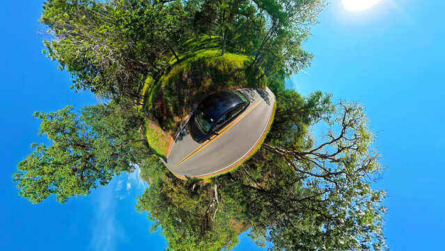 Tiny Planet View of Car on a Forest Road. Spherical panoramic view of a car driving along a winding forest road beneath a bright blue sky.