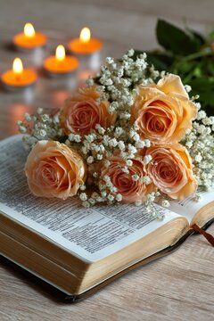 Peach roses and gypsophila resting on an open bible with glowing candles in an elegant macro shot for wedding and religious marketing