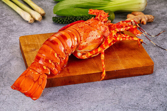Cooked lobster on wooden cutting board with fresh herbs and spices