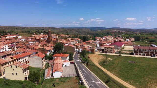 La Iglesuela del Cid in Maestrazgo, Teruel, Spain, with a baroque clock tower rising above terracotta-roofed stone buildings on an arid plateau under blue sky