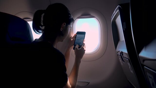 Male traveler using smartphone camera to shoot view outside airplane window. Taking pictures during flight with handheld mobile device. Airplane journey and digital photo capture concept