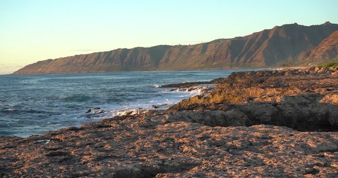 Waianae mountains rising over rocky beach at sunset, Oahu Hawaii