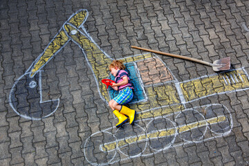 Happy little boy drawing an excavator with colorful chalk outdoors in summer. Real life, real people moment of creativity, imagination, and fun childhood playtime on the pavement. © Irina Schmidt