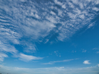 Clear blue sky with thin white clouds forming patterns resembling fish scales or ripples—specifically cirrocumulus clouds often referred to as a buttermilk sky. © saksuvan
