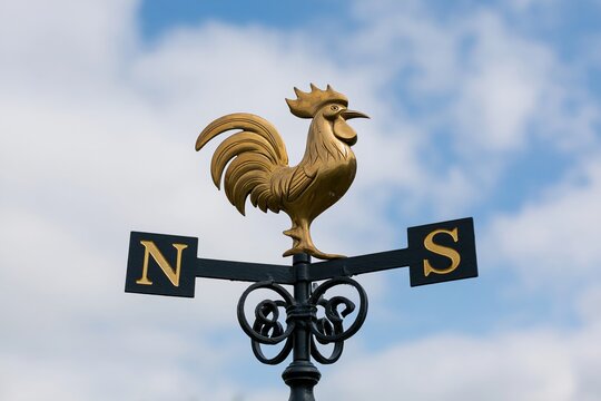 The Rooster Weather Vane atop Ornate Ironwork Against a Blue Sky