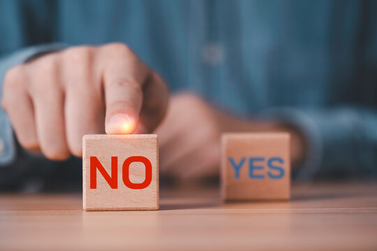 No decision concept with a finger push a wooden block labeled NO while YES remains in the background for refusal, rejection, risk avoidance, business decisions and confident choice.