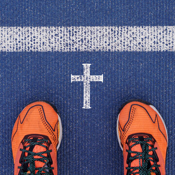 religion. Christianity, faith. feet with orange sneakers at the starting line of a running track