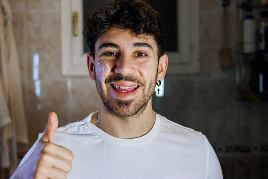Young man enjoying a skincare routine giving a thumbs up for daily wellness