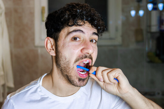 Man brushing teeth in bathroom, practicing dental hygiene and morning routine