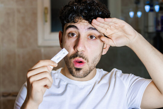 Young man receiving surprising covid-19 test result, reacting with relief