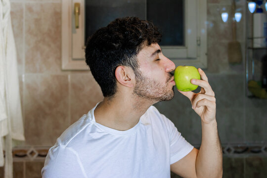 Young man embracing healthy lifestyle with green apple, focusing on wellness and self-care