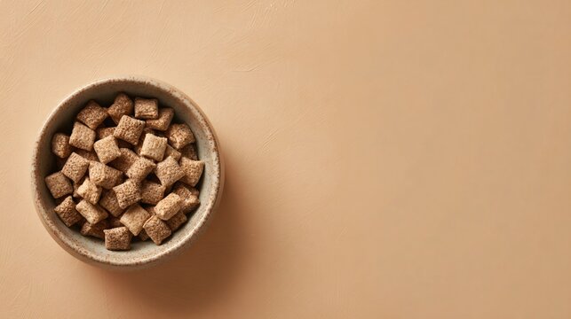 A minimalist snack arrangement featuring a small ceramic bowl of puppy chow positioned in the upper corner of a warm beige background with soft negative space