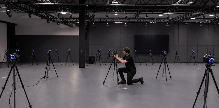 Videographer working in a professional film studio with multiple camera setups on tripods videographer production filmmaking lighting professional operator equipment technology