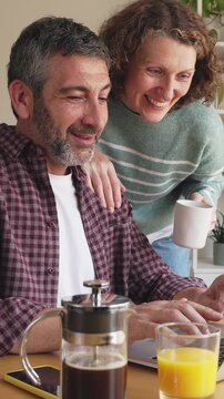 Mature couple having breakfast while working on laptop