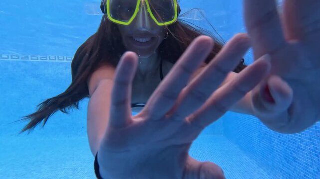 Gliding underwater, a young swimmer wears a bright yellow diving mask