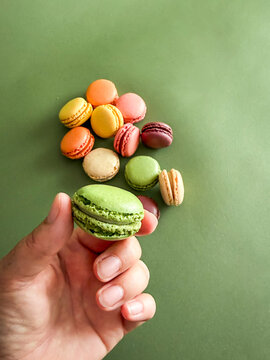 Eine weibliche Hand h&auml;lt eine gr&uuml;ne Makrone in der Hand. Draufsicht, Variation, Dessert, Frankreich. 