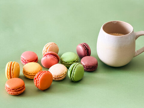Eine Tasse Kaffee und bunte Macarons auf einem gr&uuml;nen Hintergrund. Frankreich, Dessert, Kaffeepause.