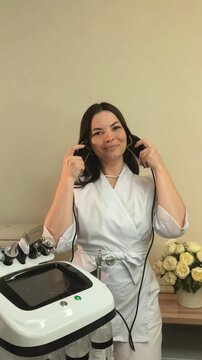 Beauty specialist demonstrates microcurrent facial handpieces beside professional equipment, cosmetic technology, salon training, skincare presentation.
