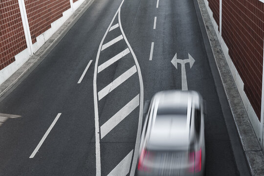 New asphalt texture background featuring an arrow indicating direction and a moving car. Top-down view.